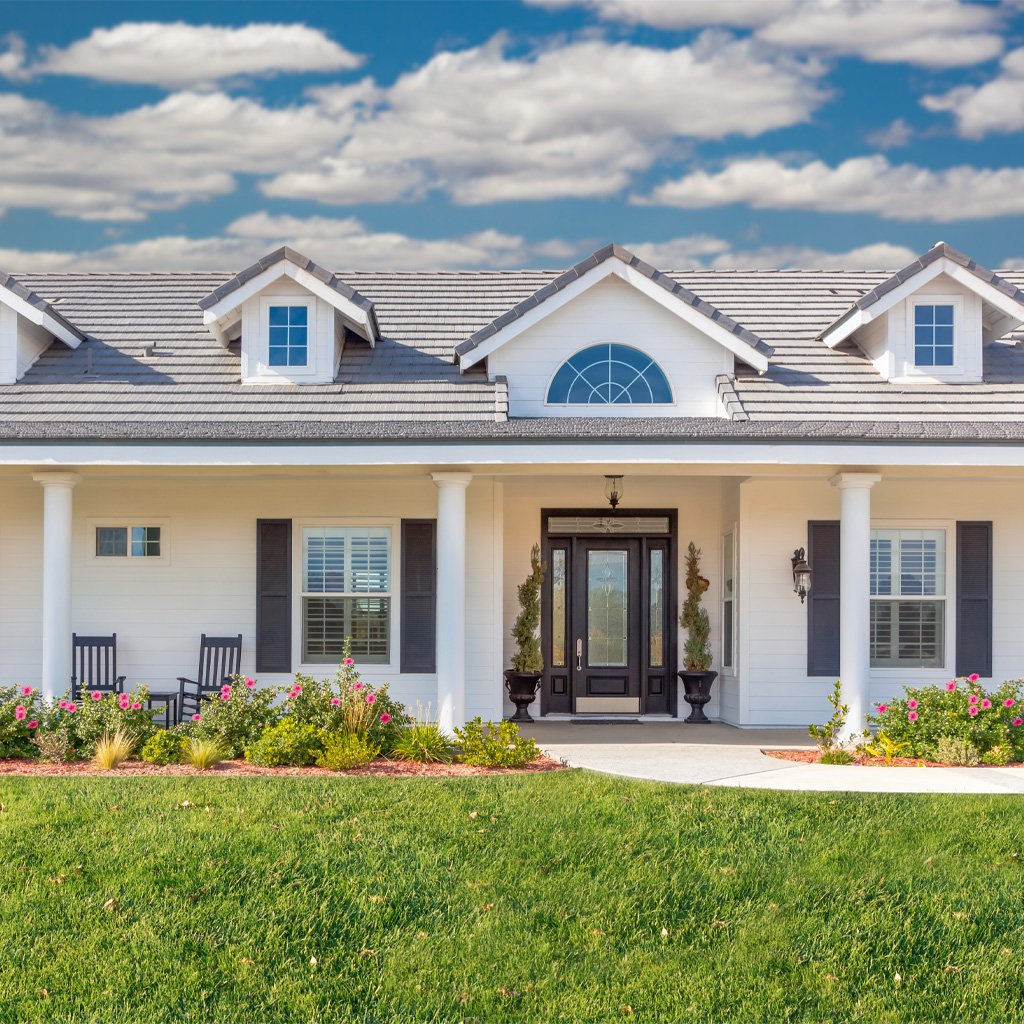 A front porch with a green lawn and a blue sky.