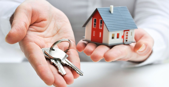 Photo of hands holding keys and a toy house.